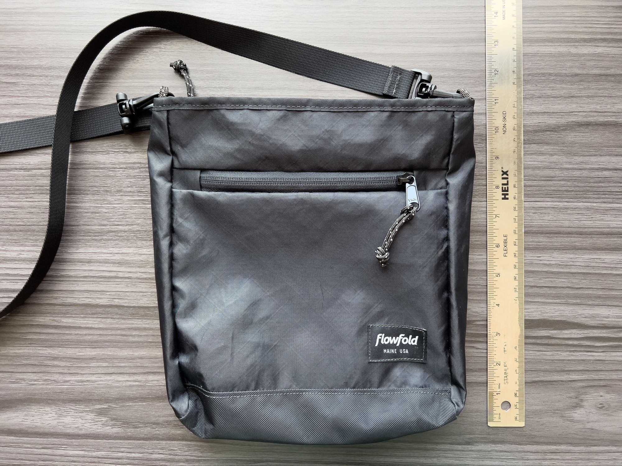 Black, lightweight shoulder bag with strap next to a metal ruler for scale.